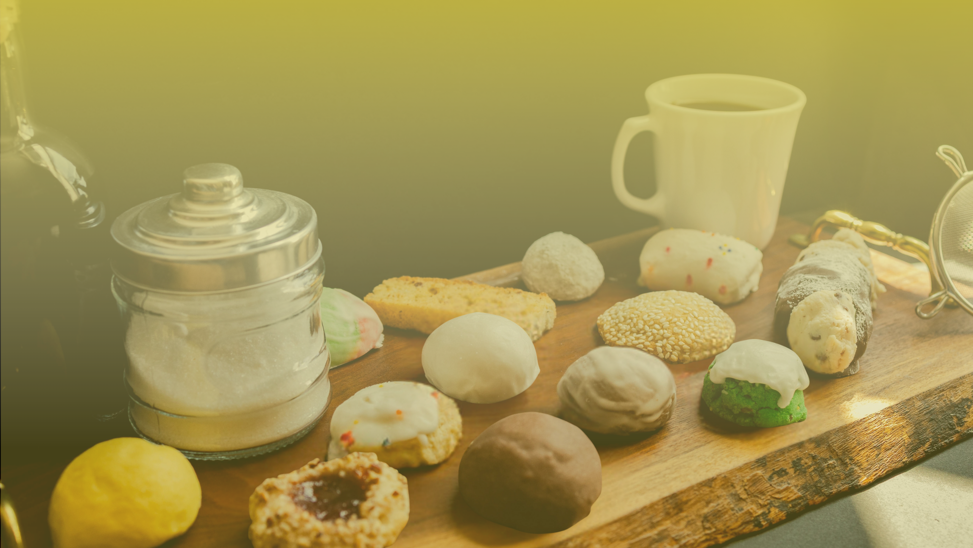 Assorted Italian cookies from Scola’s on a wooden board with coffee and sugar jar, beneath a soft yellow gradient overlay.
